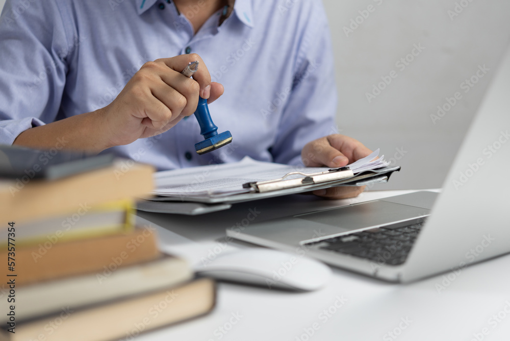 Man stamping approval of work finance banking or investment marketing documents on desk. Man stamping approval of work finance banking or investment marketing documents on desk.