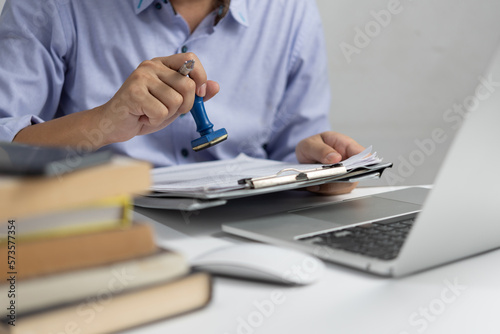 Fototapeta Man stamping approval of work finance banking or investment marketing documents on desk
