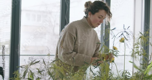 female doing new bouquet. Girl working in flower shop studio. Female florist artist cleans flowers for a beautiful bouquet, workplace view. High quality 4k footage