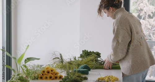 female doing new bouquet. Girl working in flower shop studio. Female florist artist cleans flowers for a beautiful bouquet, workplace view. High quality 4k footage