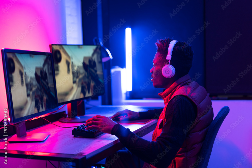 Young African man playing video game on computer. Streamer guy sitting at home and plays another match Young African man playing video game on computer. Streamer guy sitting at home and plays another match