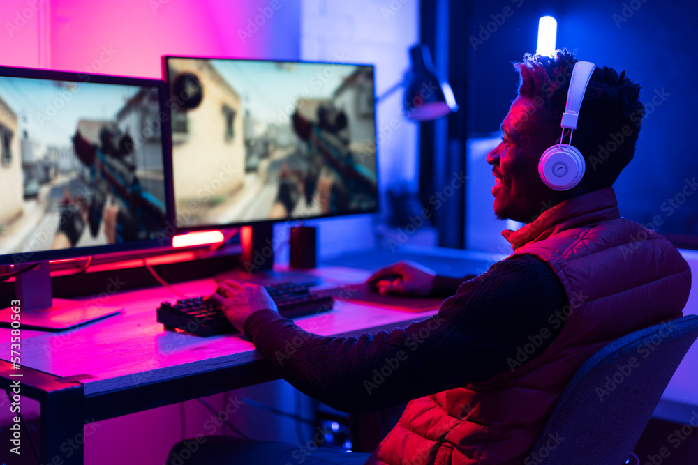 Young African man playing video game on computer. Streamer guy sitting at home and plays another match Young African man playing video game on computer. Streamer guy sitting at home and plays another match