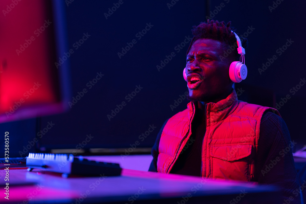 Young African man playing video game on computer. Streamer guy sitting at home and plays another match Young African man playing video game on computer. Streamer guy sitting at home and plays another match