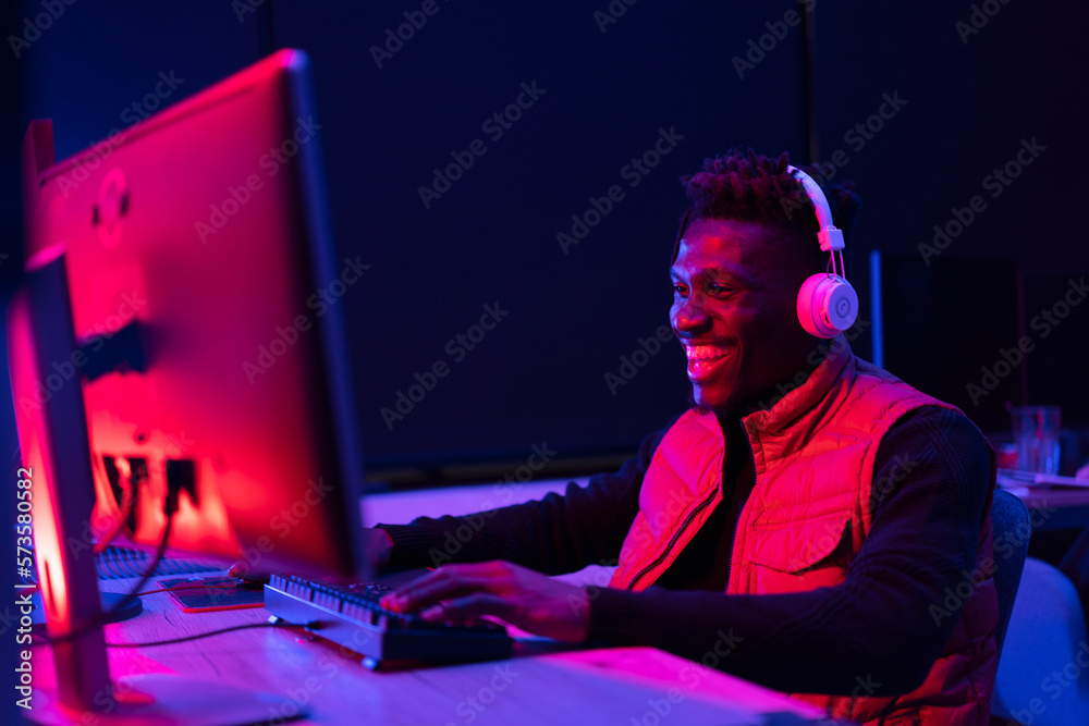Young African man playing video game on computer. Streamer guy sitting at home and plays another match Young African man playing video game on computer. Streamer guy sitting at home and plays another match