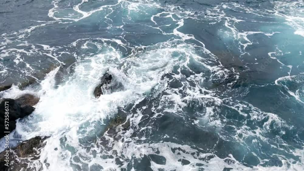 View from a height of the waves that break on the rocks of the coast. Turquoise water washes the rocks. Island coast. Coast of the ocean or sea. View from a height of the waves that break on the rocks of the coast. Turquoise water washes the rocks. Island coast. Coast of the ocean or sea.