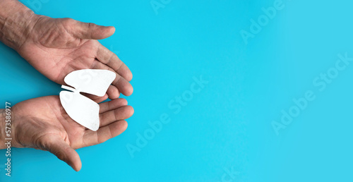 the hands of an elderly person hold a paper-cut lung organ symbol, on a blue background. Prevention of lung diseases, lung examination. Right copyspace