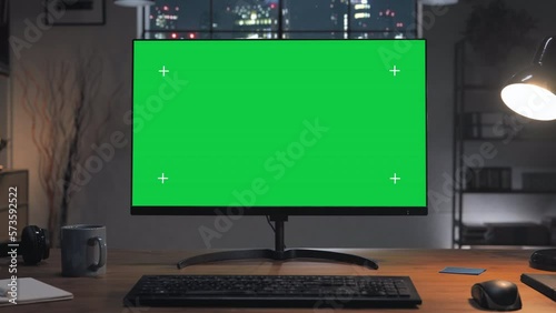 green screen computer on the home desk at night with modern city window in the background,chroma key pc monitor on the office table set up for work,remote working copy space zoom in motion