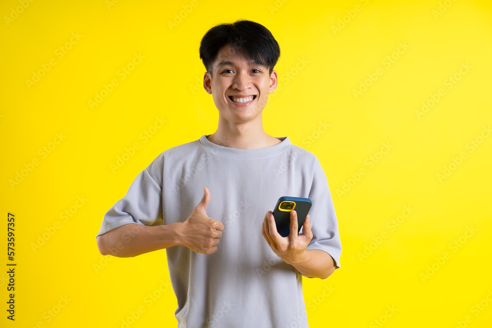 image of a handsome young man using his phone and posing on a yellow background image of a handsome young man using his phone and posing on a yellow background