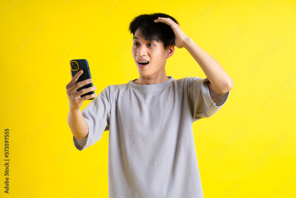 image of a handsome young man using his phone and posing on a yellow background image of a handsome young man using his phone and posing on a yellow background