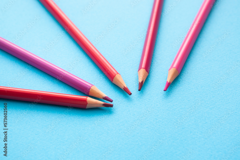 Pencils with shades of pink and red colors - on blue background, art card with stationery and copy space Pencils with shades of pink and red colors - on blue background, art card with stationery and copy space