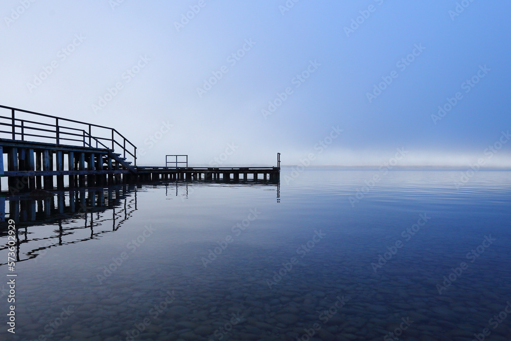 Beautiful wooden jetty and Lake Ohau in the sunset on a cold foggy day in Twizel, Canterbury, South Island, New Zealand