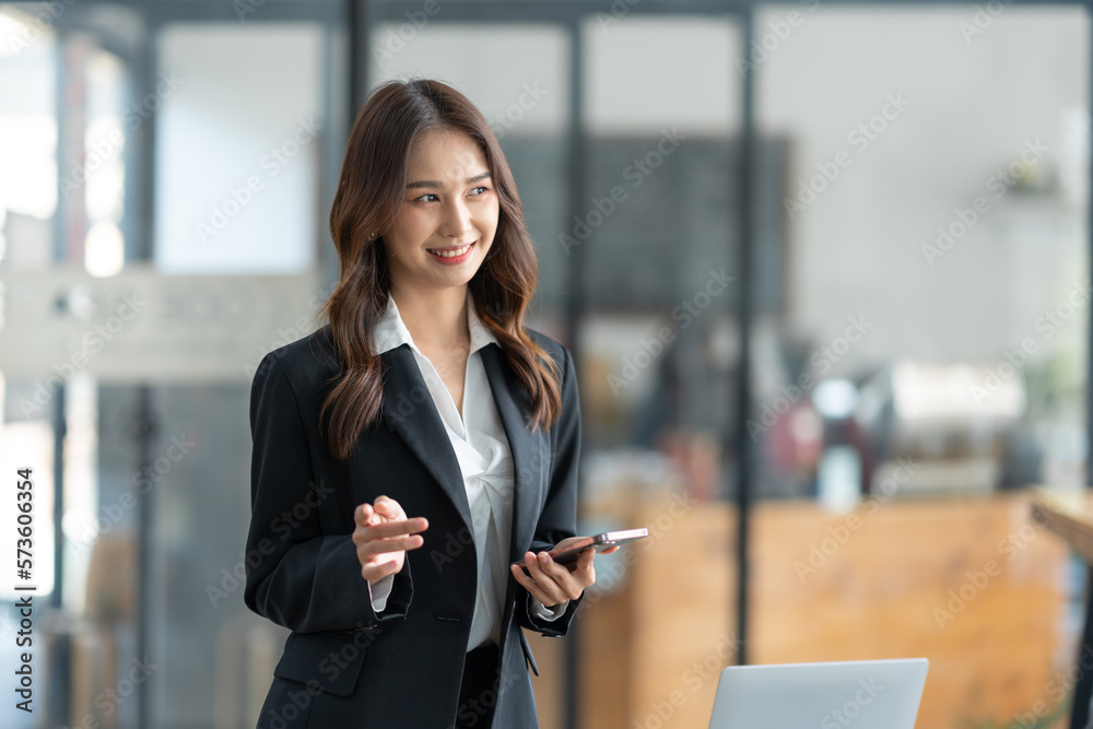 Attractive Asian businesswoman using a mobile phone at the office for making contact Talk about online business. and financial income happily. Attractive Asian businesswoman using a mobile phone at the office for making contact Talk about online business. and financial income happily.