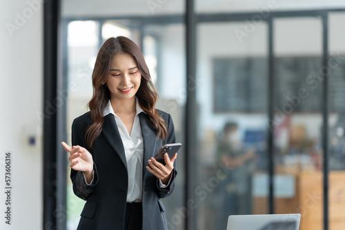 Attractive Asian businesswoman using a mobile phone at the office for making contact Talk about online business. and financial income happily.