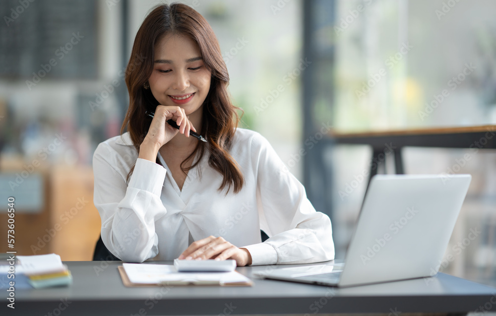 Asian businesswoman sitting in an office looking with graph detail on laptop computer Chart of real estate business growth data in the office. Asian businesswoman sitting in an office looking with graph detail on laptop computer Chart of real estate business growth data in the office.