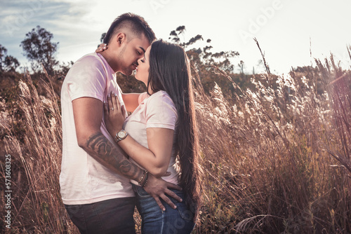 Pareja en un campo de espigas y trigo besándose en un atardecer photo