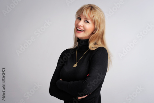 Happy blond haired mid aged woman standing againsta isolated background photo