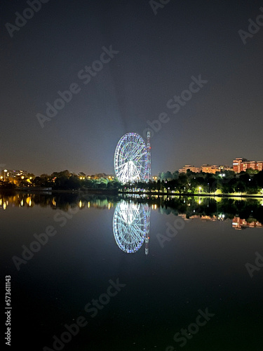 Closeup of the luna park wheel illuminated at night reflecting in the lake