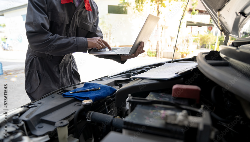 Maintenance engineer or auto mechanic checking car database usage history Enter the details in the file and in the notebook computer. Car maintenance service, mileage check.