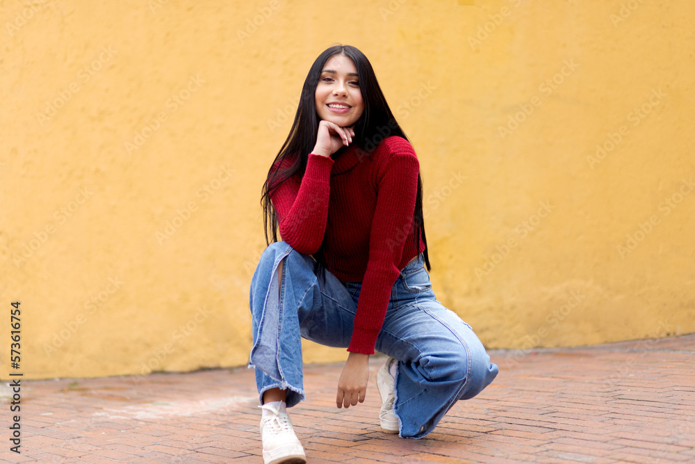 A Casual and Modern Young Woman in an Intense Red Jacket and Blue Jeans on a Yellow Blurred Background
