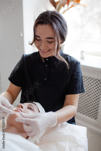 The girl lies on the coach, on a skin care procedure, improving her quality with a profesionak neautician photo