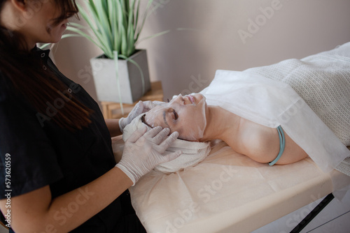 The girl lies on the coach, on a skin care procedure, improving her quality with a profesionak neautician