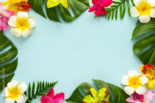 Summer background with tropical orchid flowers and green tropical palm leaves on light background. Flat lay  top view.