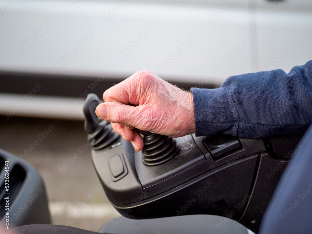 Fototapeta premium older man at work 70's driving a fork lift truck closeup of hand on the controls