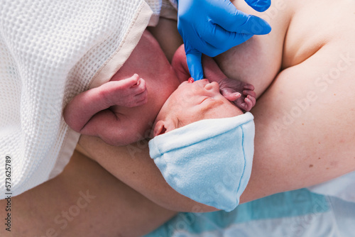 Nurse putting a finger in newborn baby mouth to check his sucking reflex. photo