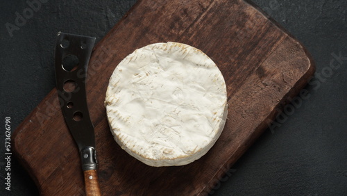 Camembert de Normandie cheese  on cutting board with knife
