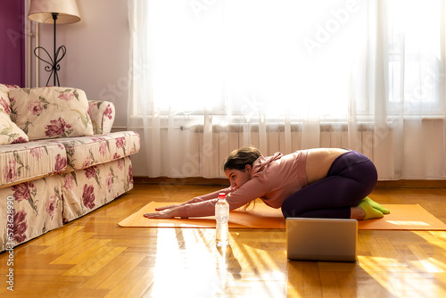 Online workout. Teen girl doing Sport exercise at home, watching tutorials on a laptop. How to keep fit indoors