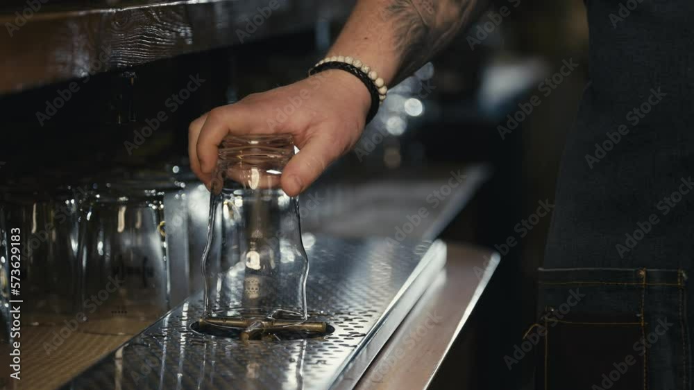 A close-up shot of a bartender cleaning a glass behind the bar. A professional takes and washes the glass before pouring the beer. High quality 4k footage A close-up shot of a bartender cleaning a glass behind the bar. A professional takes and washes the glass before pouring the beer. High quality 4k footage