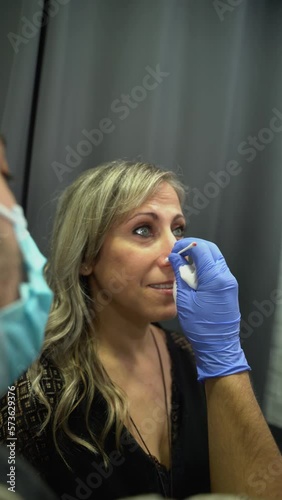 Cleaning the piercing site after performing a nose piercing on a beautiful older woman. Young spirit concept. Vertical video