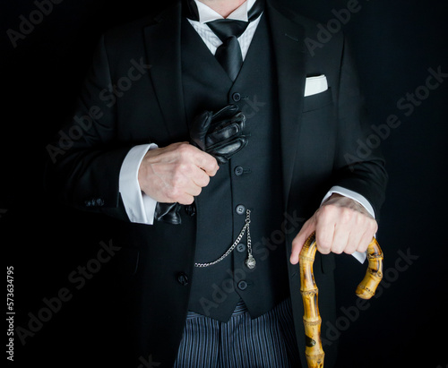 Portrait of Gentleman in Black Suit Holding Leather Gloves and Umbrella. British Businessman or Classic Butler