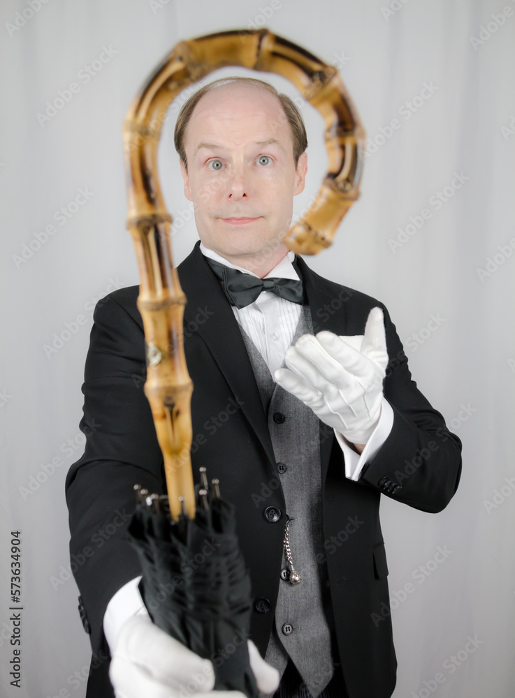 Portrait of Butler or Hotel Concierge Smiling and Offering an Umbrella. Concept of Service Industry and Professional Courtesy. Portrait of Butler or Hotel Concierge Smiling and Offering an Umbrella. Concept of Service Industry and Professional Courtesy.