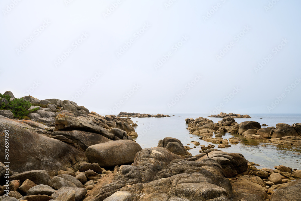 Galician beach with rocks and blue sky. Nature background.