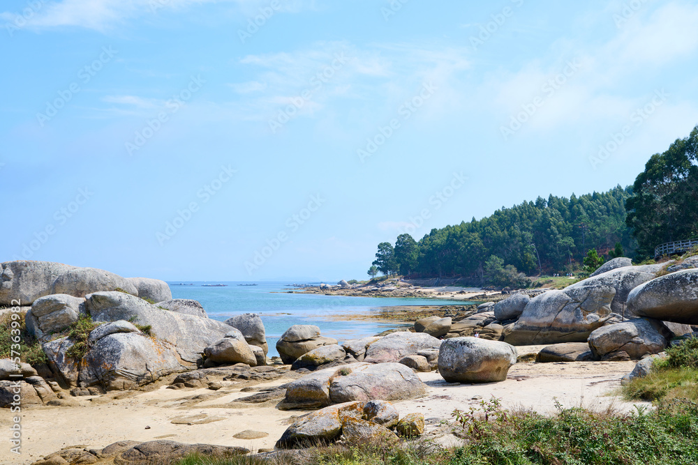 Galician beach with rocks and blue sky. Nature background.