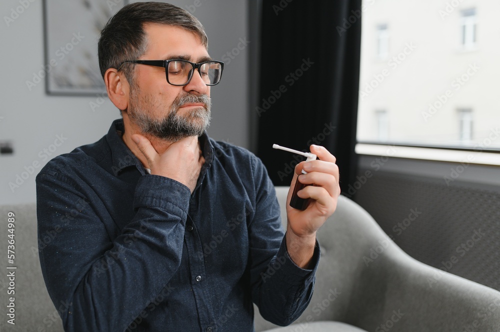 Sick senior man using throat spray at home Sick senior man using throat spray at home