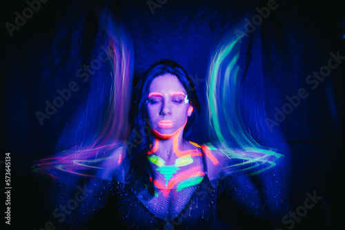 Quadro su tela Model woman in neon light, beautiful model girl with fluorescent makeup, art design of disco dancer dancing in uv light, colorful makeup