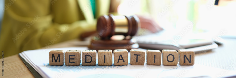 Mediator sitting near gavel of judge and words mediation closeup