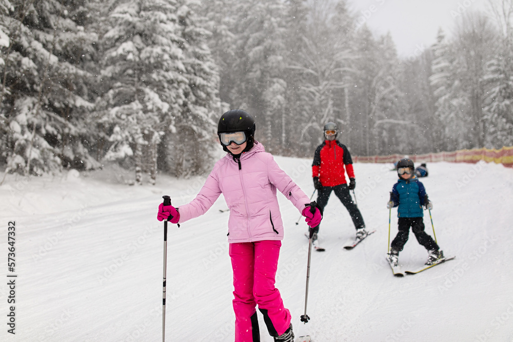 Family skiing on snowing track in ski resort