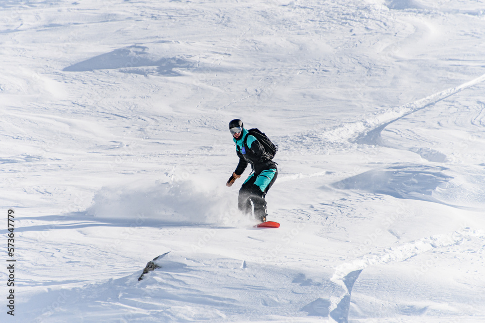 Freerider on snowboard masterfully ride down off-piste in deep fresh snow in Gudauri Georgia