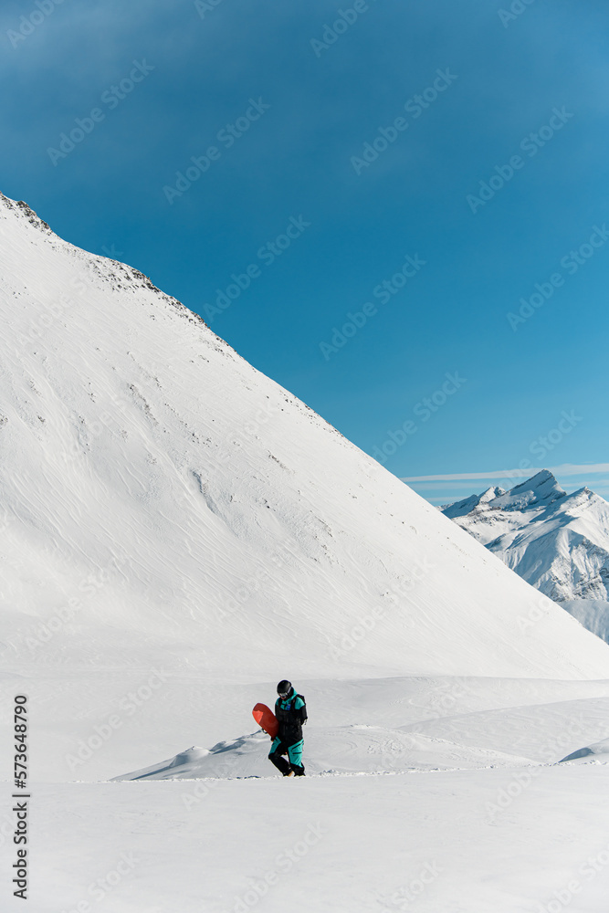 view of man freerider with snowboard walks against winter mountain landscape