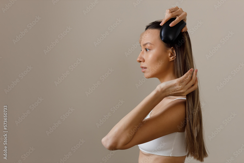 Positive smiling young woman in white top comb her long healthy well-groomed smooth hair. Cosmetic products for hair and body care. Healthy body care. Picture of profile girl on isolated background. Positive smiling young woman in white top comb her long healthy well-groomed smooth hair. Cosmetic products for hair and body care. Healthy body care. Picture of profile girl on isolated background.