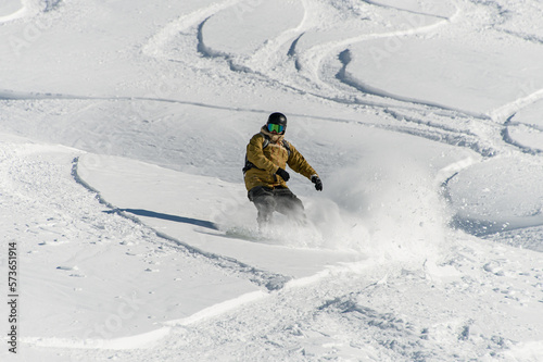 extreme man actively snowboarding on deep snow of mountain slope in winter photo