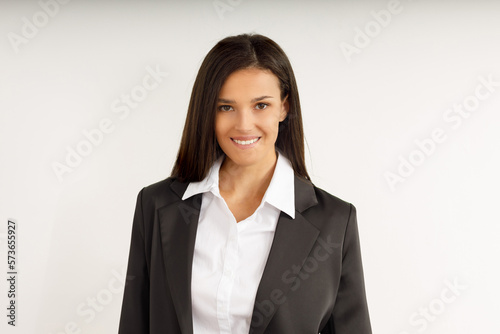Portrait of happy smiling brunette businesswoman dressed in white shirt and black jacket. Beautiful model on isolated white background. Studio shot of young attractive woman in business suit.