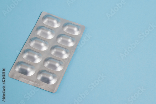 Pills in a silver blister pack on a blue paper background with copy space on the right