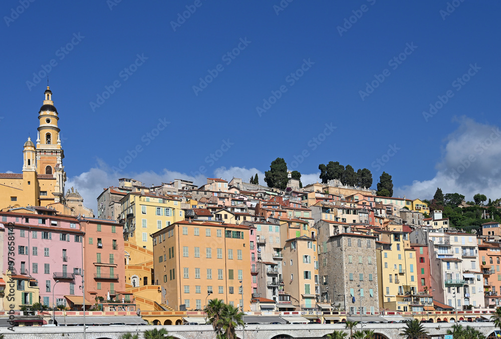 Church tower and colorful old buildings in Menton France summer season