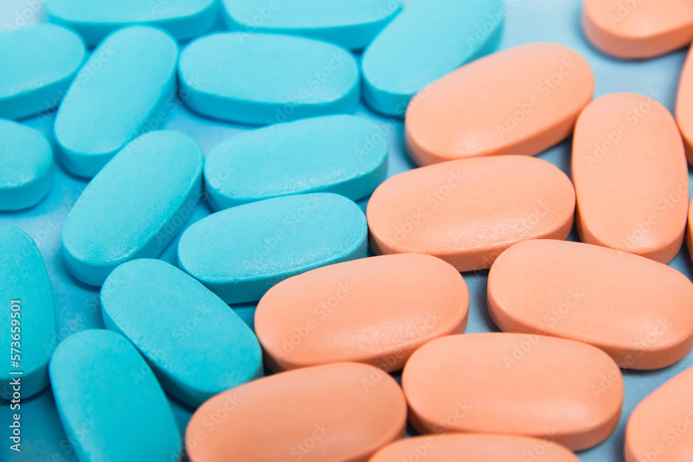 Pattern, blue and pink vitamins in pills for men and women on blue paper flatlay background. The concept of differences in the needs of the female and male gender Pattern, blue and pink vitamins in pills for men and women on blue paper flatlay background. The concept of differences in the needs of the female and male gender