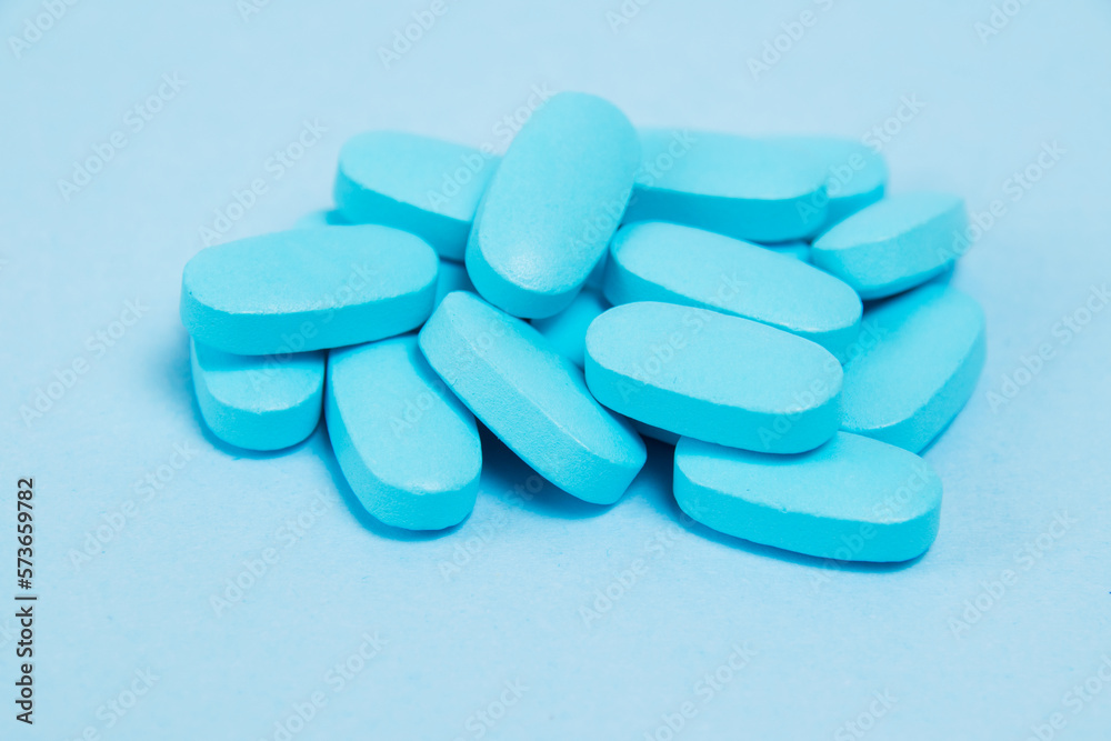 Many pills, vitamins for men on blue background, side view Many pills, vitamins for men on blue background, side view