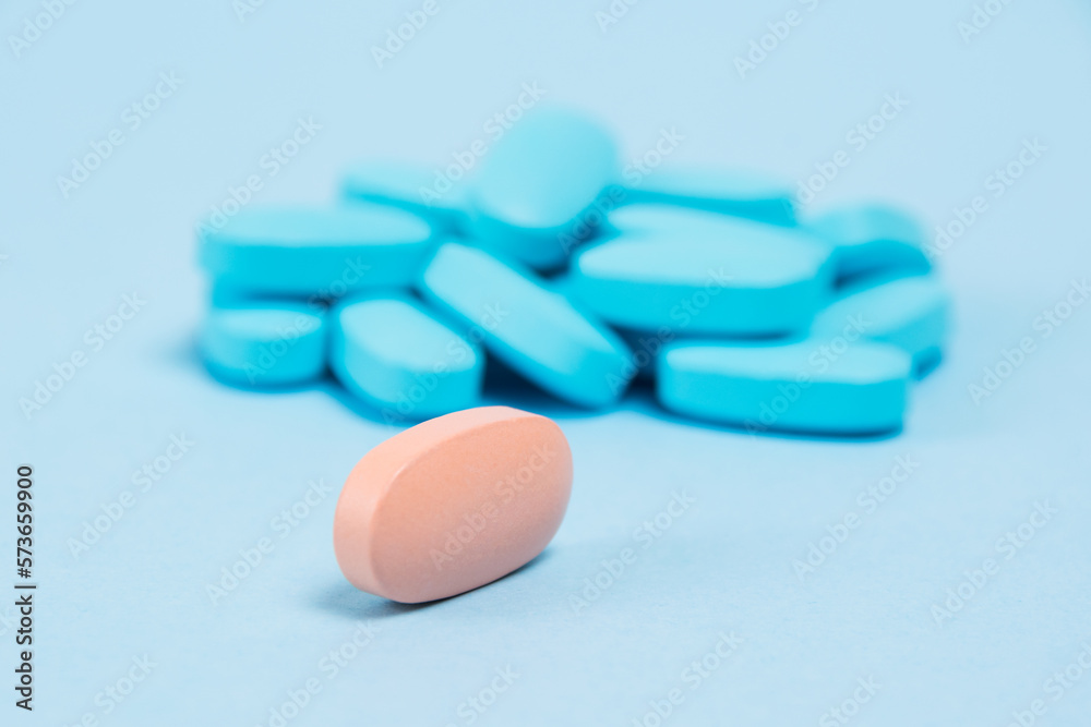 Pink pill macro, multicolored pills on blue background with copy space